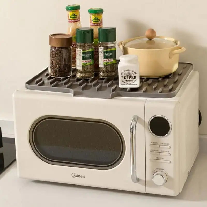 White microwave with a black tray holding kitchen items on a white surface.