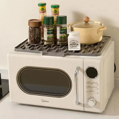 White microwave with a black tray holding kitchen items on a white surface.